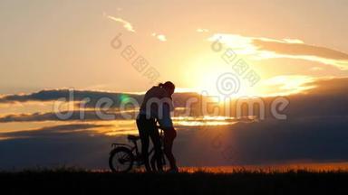 <strong>剪影</strong>自行车可爱的家庭在草地上日落时间。母亲和婴儿在日落时骑自行车的<strong>剪影</strong>。生活方式
